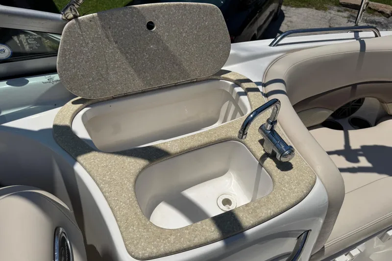 Slide: The Image of 2006 Chaparral 256 SSi boat interior with sink and faucet, featuring beige seating. - 16