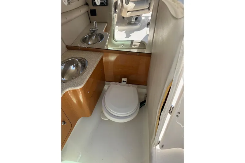 Slide: The Image of 2006 Chaparral 256 SSi boat interior with compact bathroom, featuring sink and toilet. - 28