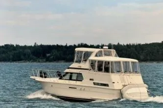 The Image of 1991 Hatteras 40 Double Cabin cruising on a serene lake with forested shoreline. - 0