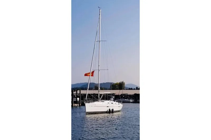 Slide: The Image of 2007 Beneteau 343 sailboat docked on calm water with a red flag. - 4