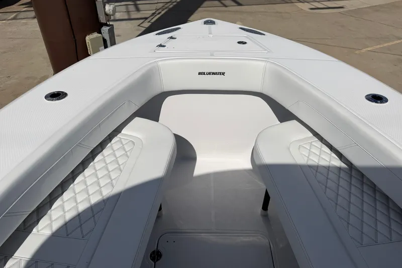 Slide: The Image of 2026 Bluewater Sportfishing 25T boat interior with white seating and diamond stitching. - 25