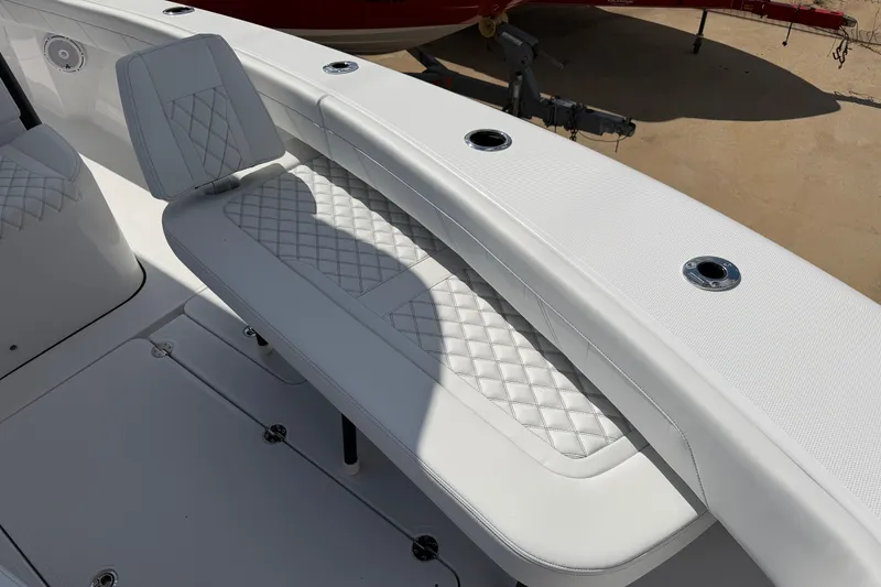Slide: The Image of 2026 Bluewater Sportfishing 25T boat interior with white quilted seating and rod holders. - 26
