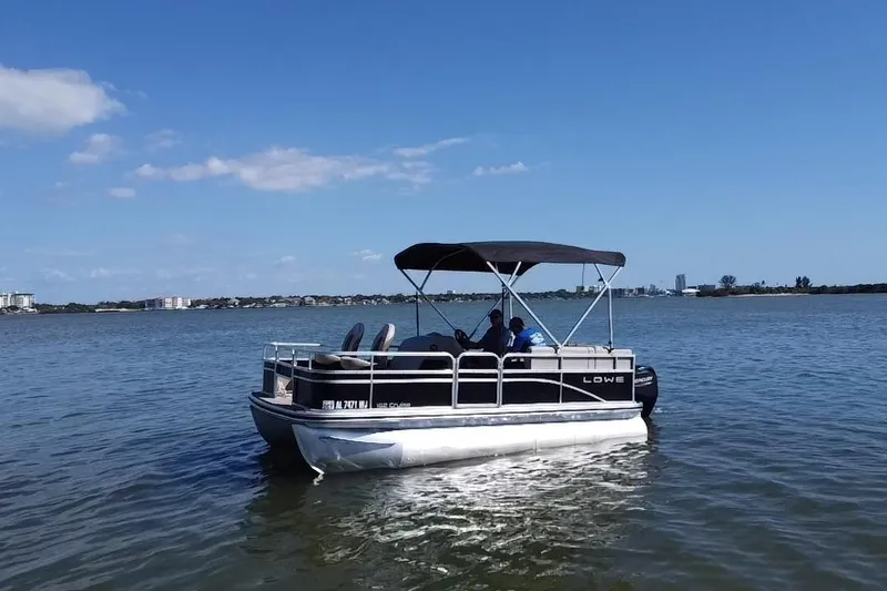 Slide: The Image of 2023 Lowe Ultra 162 Fish & Cruise pontoon boat on calm water under clear blue sky. - 18
