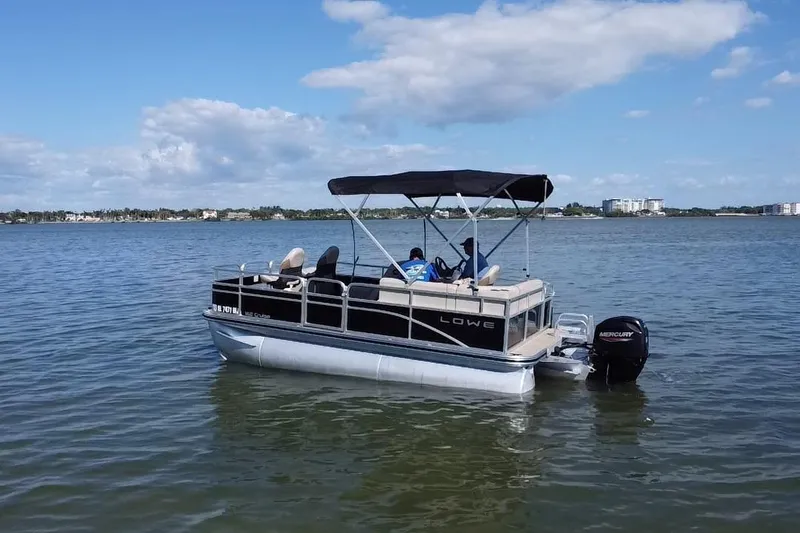 Slide: The Image of 2023 Lowe Ultra 162 Fish & Cruise pontoon boat on calm water under blue sky. - 19