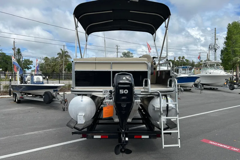 Slide: The Image of 2023 Lowe Ultra 162 Fish & Cruise pontoon boat with Mercury 50 HP engine, parked outdoors. - 3