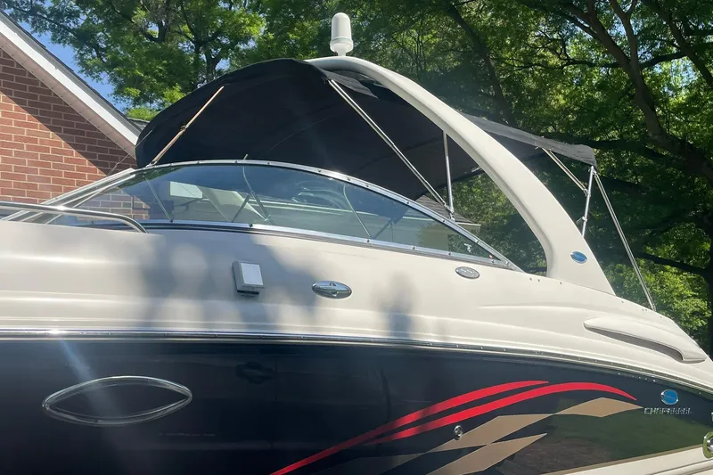 Slide: The Image of 2005 Chaparral 265 SSi boat with canopy, parked near a brick building. - 5