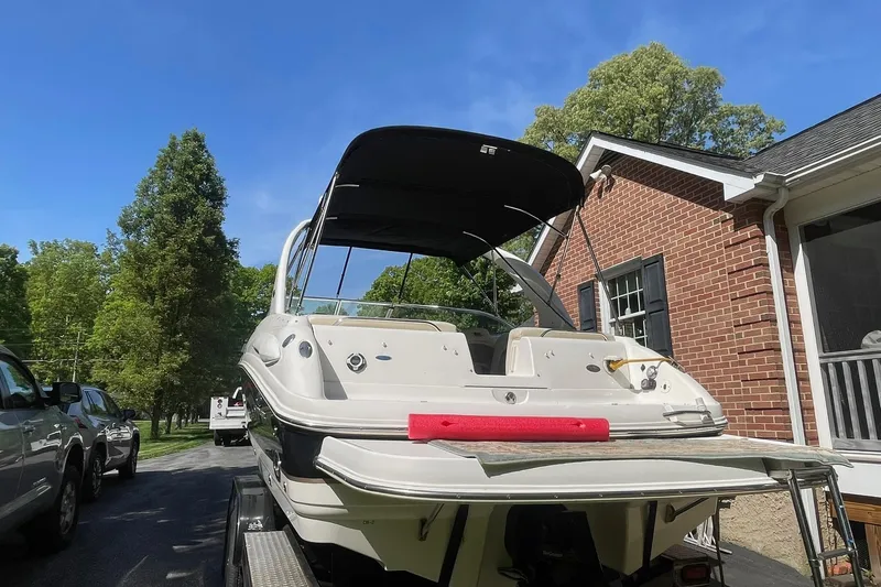 Slide: The Image of 2005 Chaparral 265 SSi boat parked near a brick house under a clear blue sky. - 6