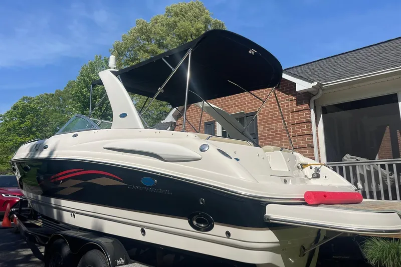 Slide: The Image of 2005 Chaparral 265 SSi boat with canopy, parked near a brick house. - 7