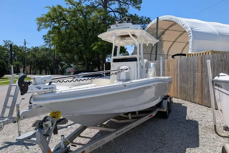 Slide: The Image of 2023 Ranger 2660 Bay boat on trailer, parked outdoors near a covered storage area. - 3