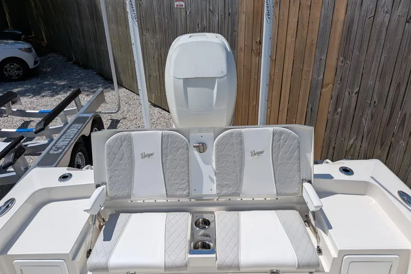 Slide: The Image of 2023 Ranger 2660 Bay boat with cushioned seating and motor, parked on a trailer. - 5