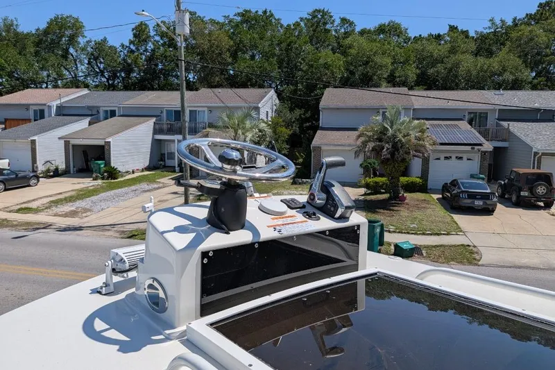 Slide: The Image of 2023 Ranger 2660 Bay boat helm with steering wheel and controls, parked in a residential area. - 9