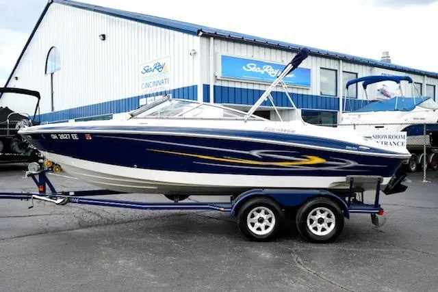 The Image of 2006 Four Winns 210 Horizon boat on trailer, parked outside dealership. - 1