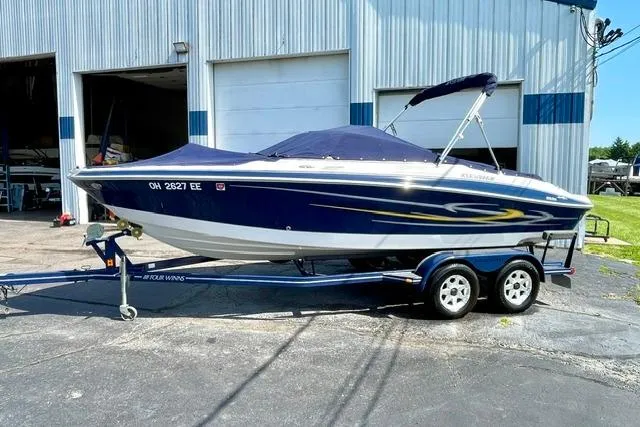 Slide: The Image of 2006 Four Winns 210 Horizon boat on trailer, parked outside a garage. - 19