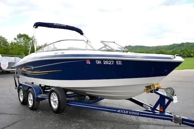Slide: The Image of 2006 Four Winns 210 Horizon boat on trailer, blue and white design, parked outdoors. - 3