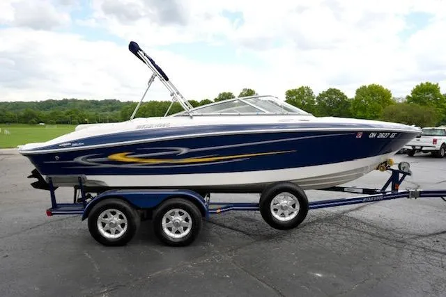Slide: The Image of 2006 Four Winns 210 Horizon boat on trailer, blue and white design, parked outdoors. - 4