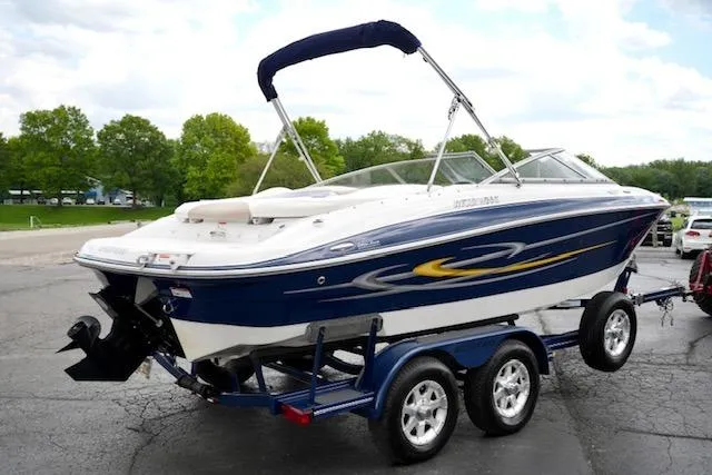 Slide: The Image of 2006 Four Winns 210 Horizon boat on trailer, blue and white design, parked outdoors. - 5