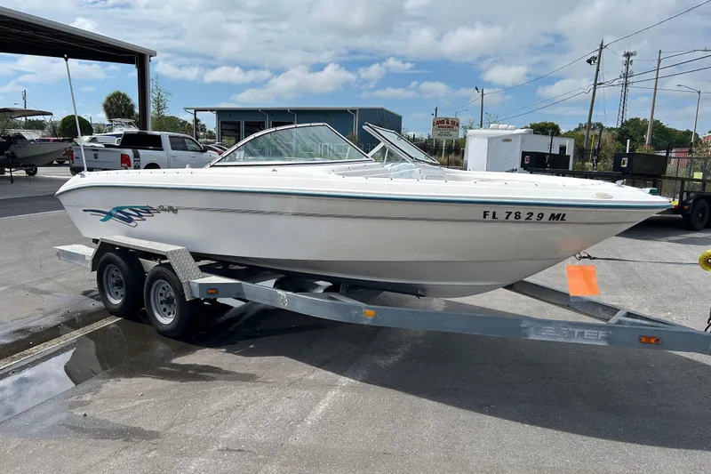 The Image of 1995 Sea Ray 195 Sport boat on trailer, parked outdoors under a cloudy sky. - 1