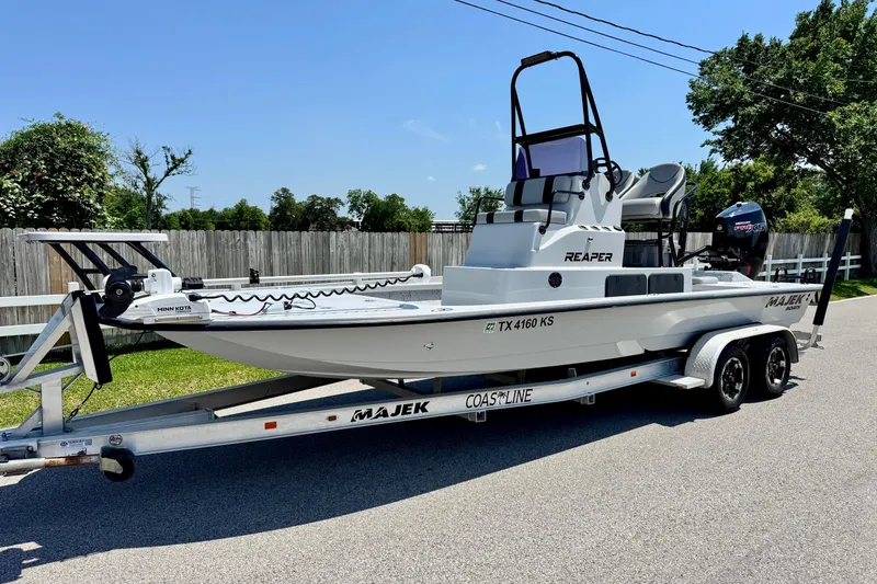 The Image of 2022 Majek 24 Reaper boat on trailer, parked on a sunny street. - 1