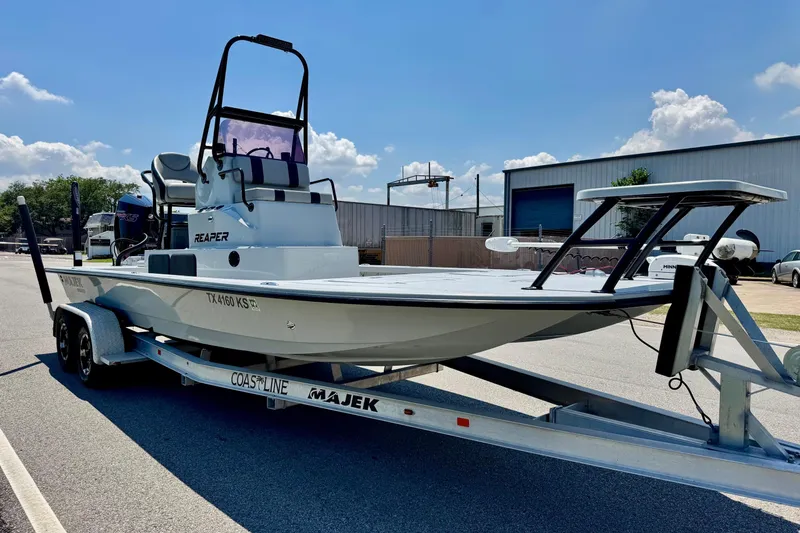 Slide: The Image of 2022 Majek 24 Reaper boat on trailer, parked outdoors under a clear blue sky. - 5
