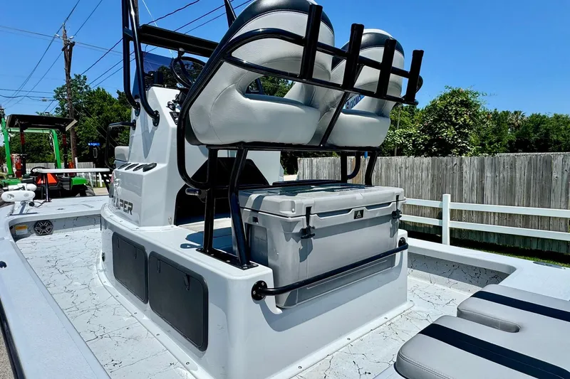 Slide: The Image of 2022 Majek 24 Reaper boat with seating and storage, parked outdoors on a sunny day. - 8