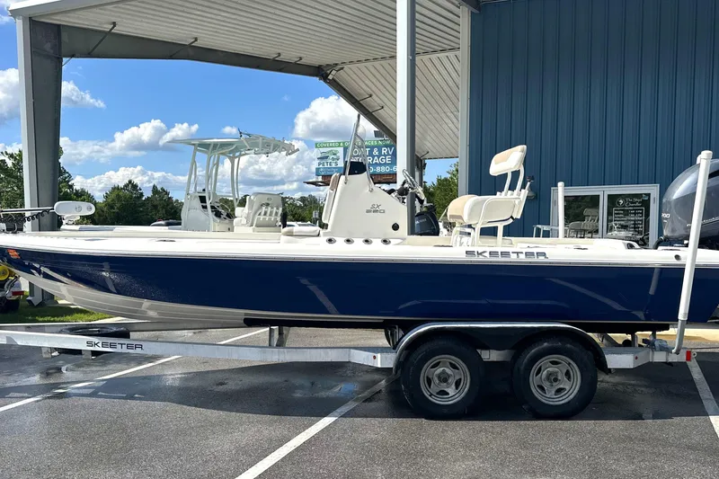 Slide: The Image of 2015 Skeeter SX220 T boat on trailer under canopy, parked outdoors. - 2