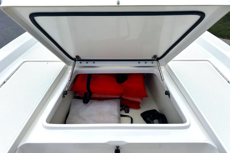 Slide: The Image of Open storage compartment on 2015 Skeeter SX220 T boat with life jackets inside. - 26