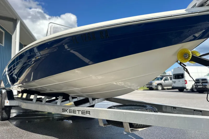Slide: The Image of 2015 Skeeter SX220 T boat on trailer, parked outdoors under blue sky. - 4