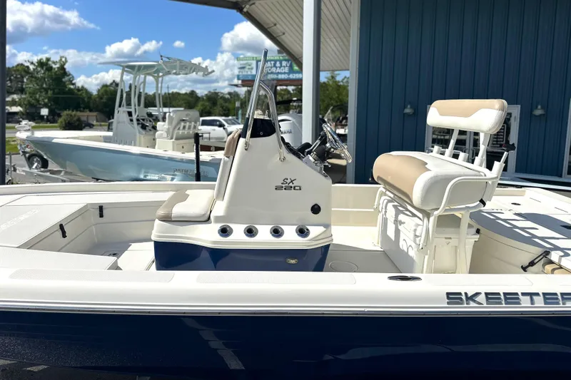 Slide: The Image of 2015 Skeeter SX220 T boat with beige seating, parked outdoors under a blue sky. - 8