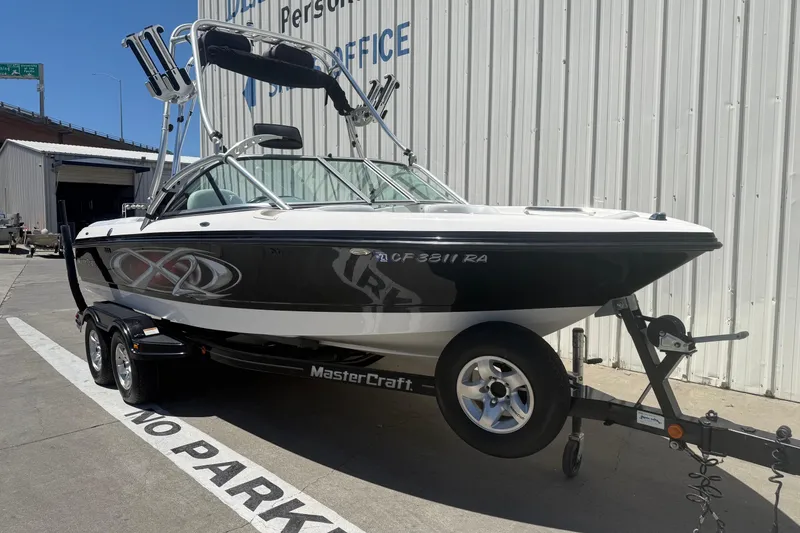 Slide: The Image of 2003 MasterCraft X2 boat on trailer, parked outside a warehouse. - 1