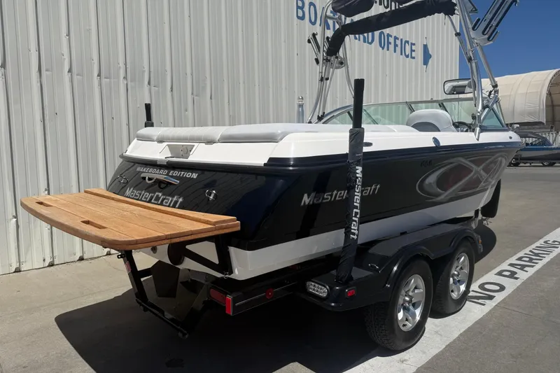 Slide: The Image of 2003 MasterCraft X2 Wakeboard Edition boat on trailer, parked near a building. - 6