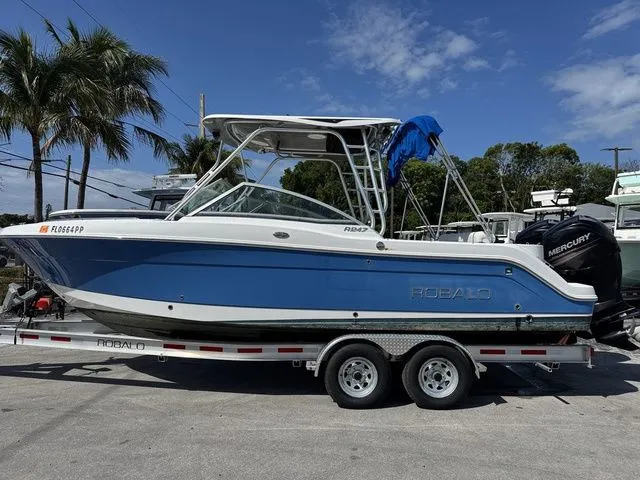 Slide: The Image of 2012 Robalo 247 DC boat on trailer, blue hull, sunny day. - 4