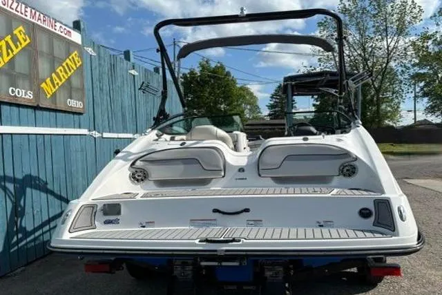 Slide: The Image of 2016 Yamaha Boats 212X, white, rear view, parked outdoors near blue fence. - 4
