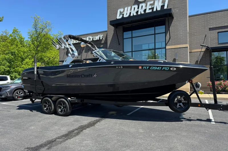 The Image of 2021 MasterCraft X26 boat on trailer outside dealership, sunny day. - 1
