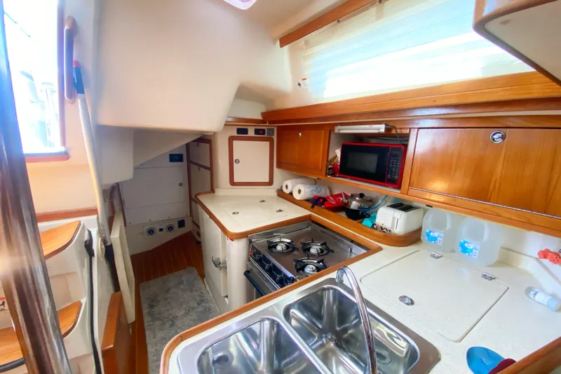Slide: The Image of 2004 Catalina 42 MkII yacht kitchen with stove, sink, and wooden cabinetry. - 24
