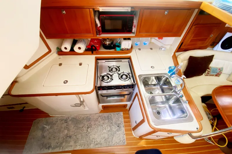 Slide: The Image of Interior of 2004 Catalina 42 MkII yacht kitchen with stove, sink, and wooden cabinetry. - 22