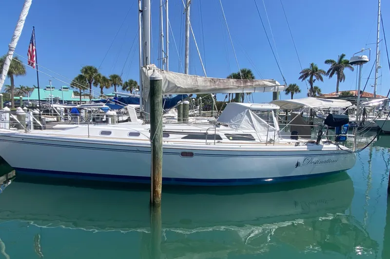 Slide: The Image of 2004 Catalina 42 MkII sailboat docked in a sunny marina with palm trees. - 2