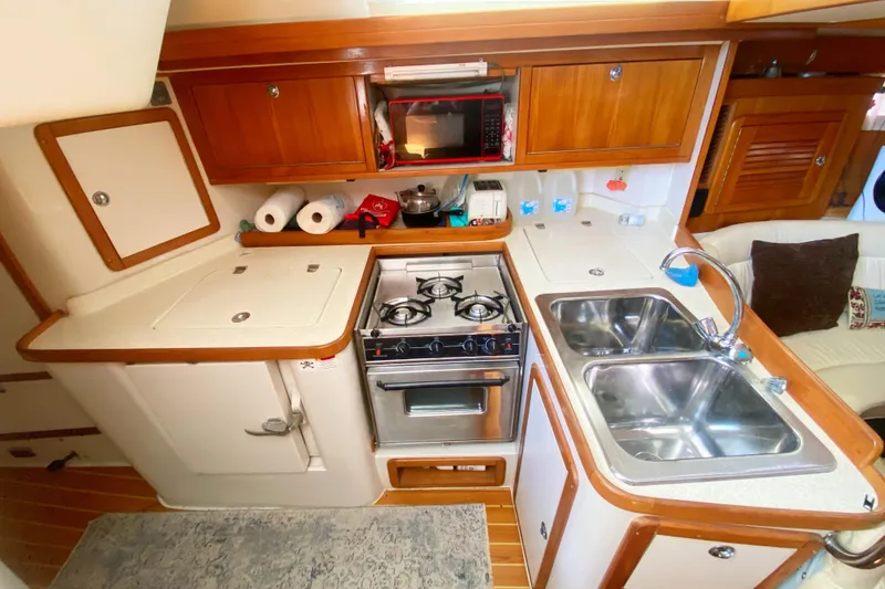 Slide: The Image of Cozy kitchen in a 2004 Catalina 42 MkII yacht with stove, sink, and wooden cabinets. - 23