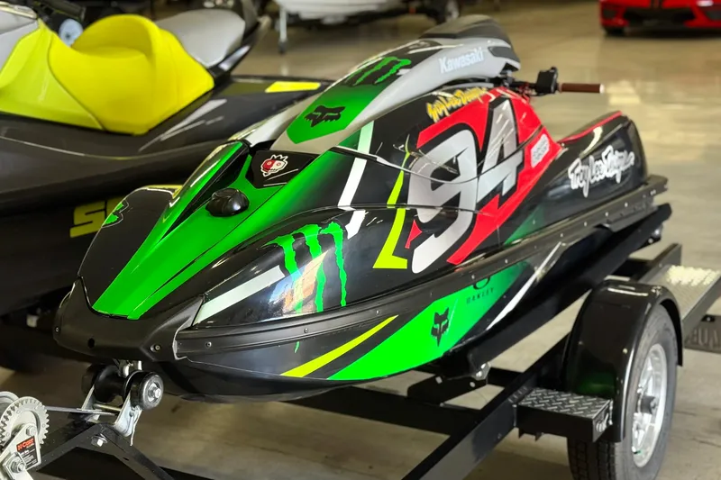 Slide: The Image of 2024 Kawasaki Jetski SX-R with vibrant green and red racing graphics on a trailer. - 2