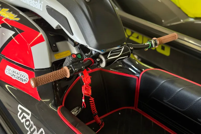 Slide: The Image of 2024 Kawasaki Jetski SX-R handlebars with red accents and brown grips. - 6