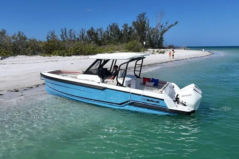 Slide: The Image of Wellcraft 28 T-Top 2026 boat on beach with clear water. - 2
