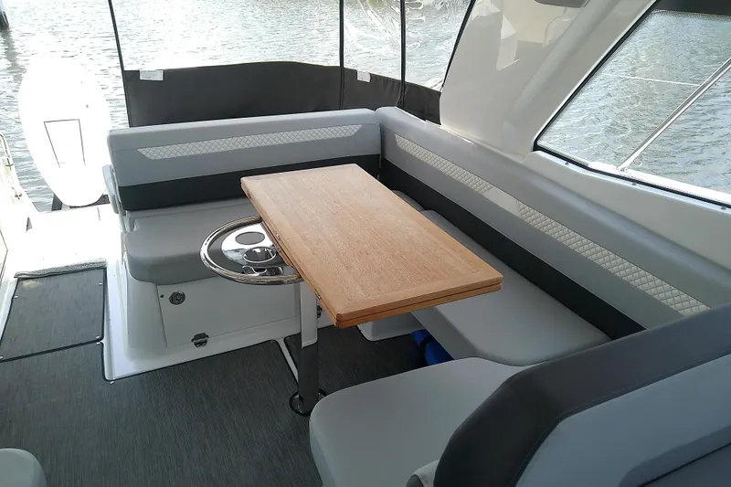 Slide: The Image of 2024 Beneteau Gran Turismo 36 cockpit with seating and wooden table, overlooking water. - 26