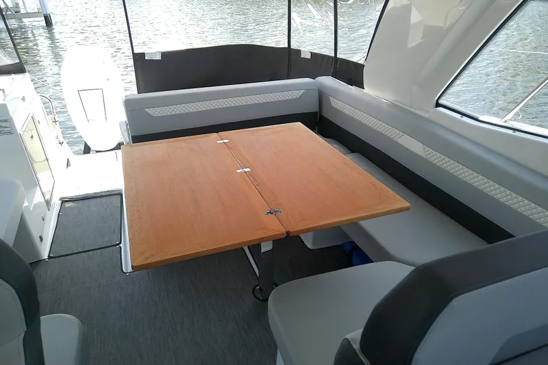 Slide: The Image of Interior of 2024 Beneteau Gran Turismo 36, featuring a wooden table and cushioned seating. - 27