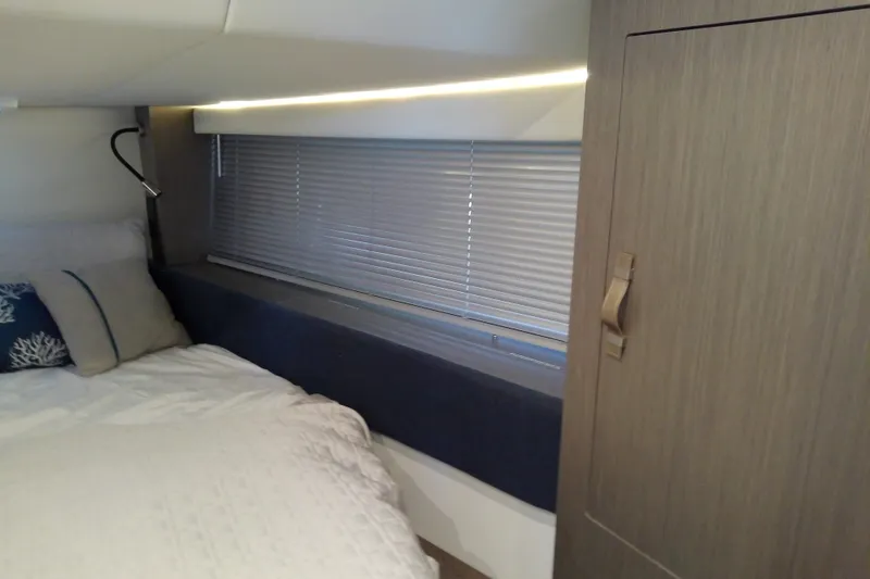 Slide: The Image of 2024 Beneteau Gran Turismo 36 cabin interior with bed, window blinds, and wooden cabinet. - 82