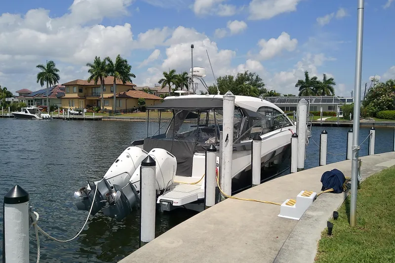 Slide: The Image of 2024 Beneteau Gran Turismo 36 yacht docked by waterfront homes, under a partly cloudy sky. - 9