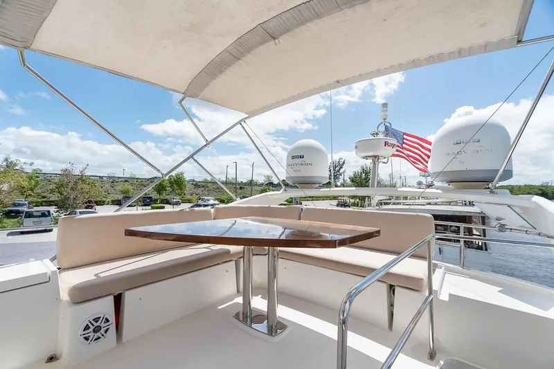 Slide: The Image of Luxurious 2016 Prestige 500 yacht deck with seating, table, and American flag under sunny skies. - 31