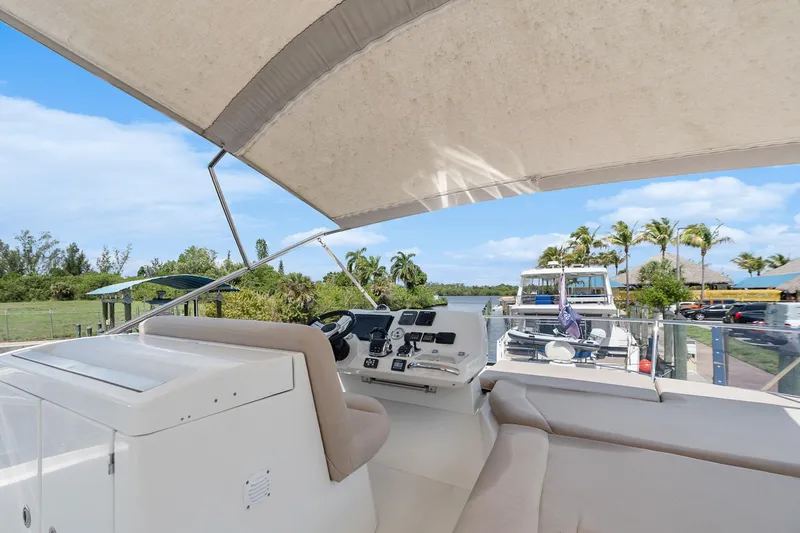 Slide: The Image of Flybridge of 2016 Prestige 500 yacht with helm, seating, and canopy in marina setting. - 32