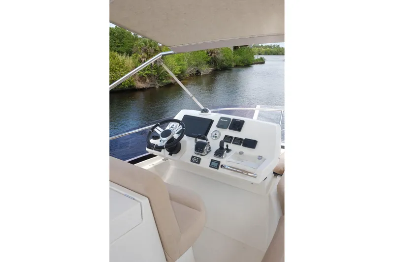 Slide: The Image of Helm of 2016 Prestige 500 yacht with modern controls, overlooking serene waterway. - 68