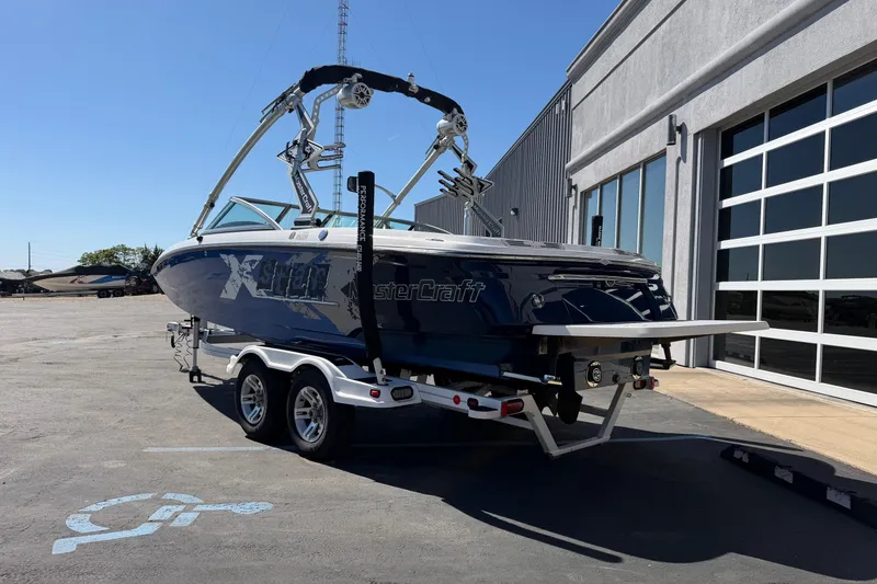 Slide: The Image of 2010 MasterCraft XStar boat on trailer, parked outside a building under clear blue sky. - 3