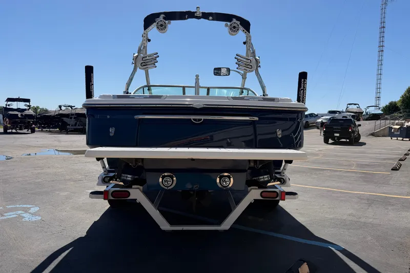 Slide: The Image of 2010 MasterCraft XStar boat, rear view in a parking lot under clear blue sky. - 4