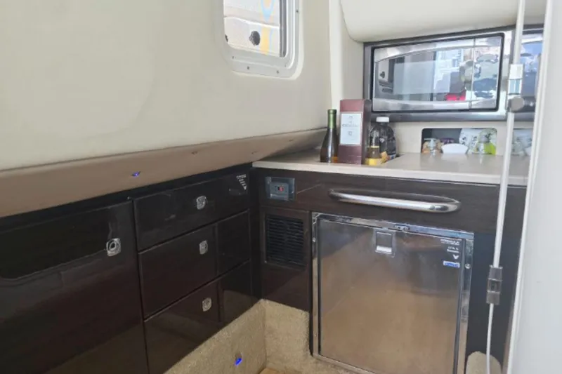 Slide: The Image of Interior of 2015 Formula 350 Crossover Bowrider I/O, featuring kitchenette with storage and appliances. - 16